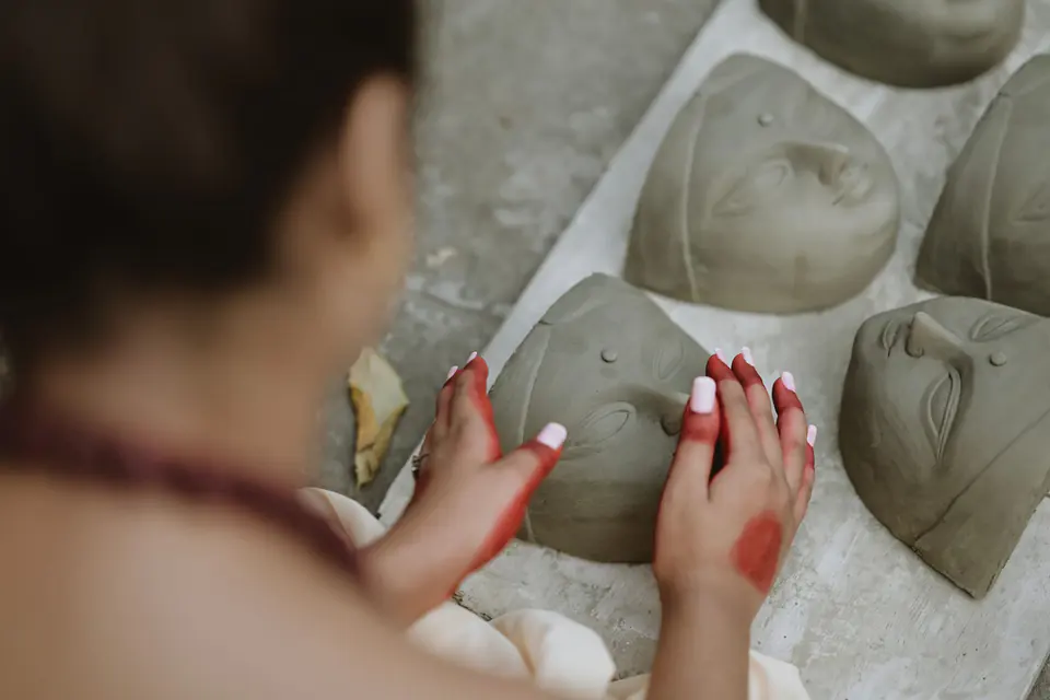 Hands shaping mask forms in a prop workshop