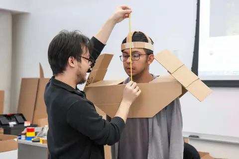 착용자에게 판지 헬멧과 어깨 장식을 맞추는 모습